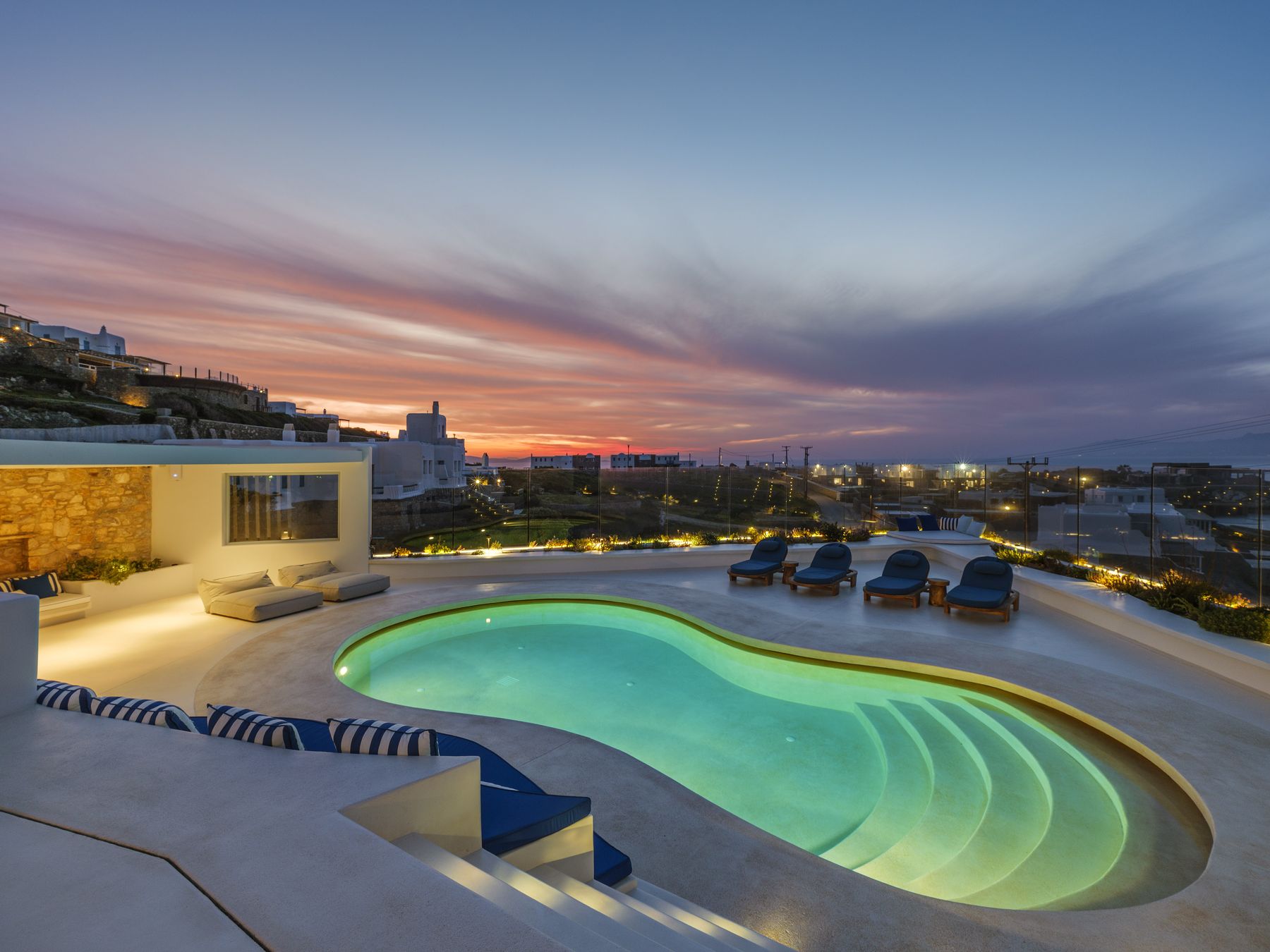 The pool lit up under a pink sunset sky